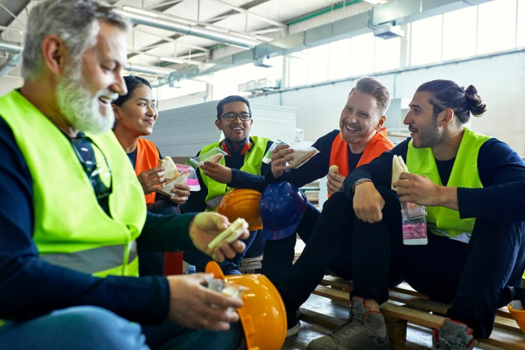 grupa robotników spożywa śniadanie na hali